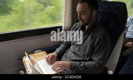 Creative man designer working on his laptop computer in a train. Stock Photo