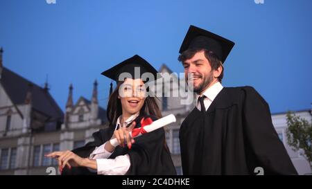 Happy young graduates dancing and celebrating graduation in park Stock Photo