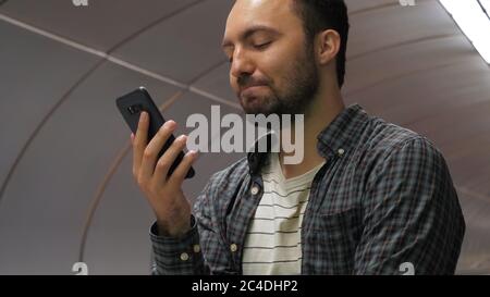Casual smiling man finishes talking on the phone on a escalator Stock Photo