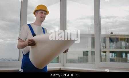 Worker looking at blueprint and checking the interior he is in. Stock Photo