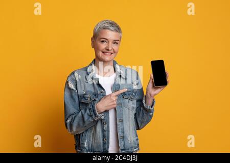 Great App. Smiling Mature Lady Pointing At Smartphone With Black Screen Stock Photo