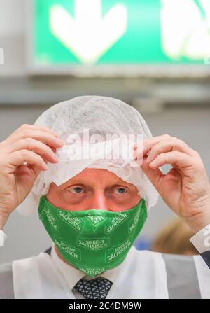 Leipzig, Germany. 26th June, 2020. Michael Kretschmer (CDU), Prime Minister of Saxony, is putting on a hairnet for hygienic reasons in a logistics centre jointly operated by DHL and Philip Morris Germany. In the so-called fulfillment hub, DHL will take over the control of incoming goods, storage, picking and packing of the goods and will take care of shipping and returns management. Credit: Jan Woitas/dpa-Zentralbild/dpa/Alamy Live News Stock Photo