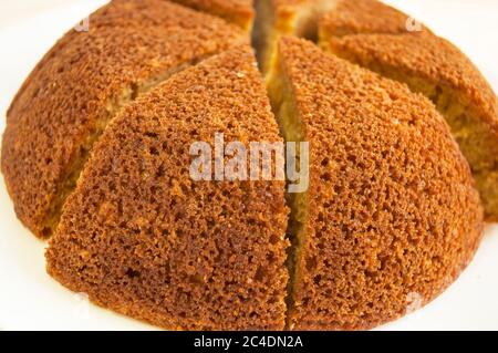 Sliced, divided sponge pie into portions on a white background close up. Minimalist appearance. Stock Photo