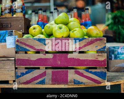 Closeup shot of a wooden fruit crate with the flag of UK drawn on it full of green apples Stock Photo