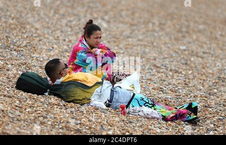 A couple keep warm on the beach in Brighton as thunderstorms and torrential rain are forecast to sweep across the UK, bringing an end to a week of blazing sunshine and scorching temperatures. Stock Photo