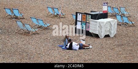 A couple on the beach near empty deck chairs in Brighton as thunderstorms and torrential rain are forecast to sweep across the UK, bringing an end to a week of blazing sunshine and scorching temperatures. Stock Photo