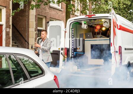 Man playing saxophone from a party van on the street in The Hague Stock Photo
