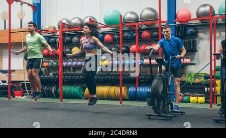 Athletes doing air bike and skipping rope Stock Photo