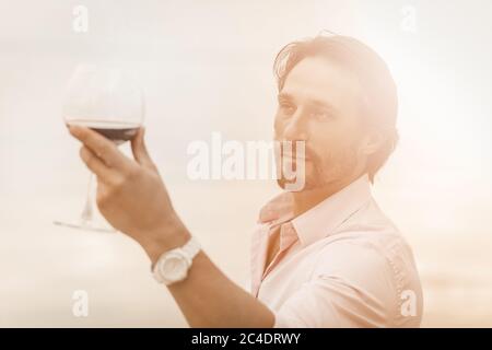 Handsome Caucasian man with glass of red wine on white background. Holiday or festive toast concept. Tinted image Stock Photo