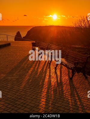 A red burning sunset with the silhouett of a cliff over the sea in park Stock Photo