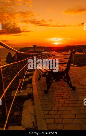 A red burning sunset with the silhouett of a cliff over the sea in park Stock Photo
