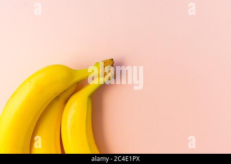yellow bunch of ripe bananas on a pink paper background, copyspace, horizontal position Stock Photo