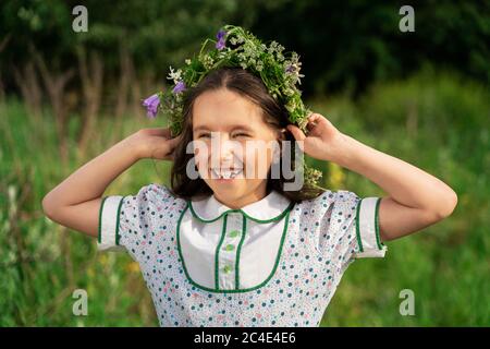 a girl with long hair and a wreath of flowers laughs Stock Photo