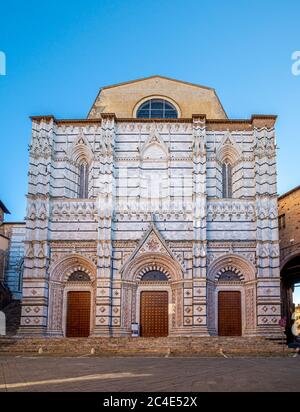 Tourists sitting on the steps to the cathedral baptistery of St John. Siena. Stock Photo