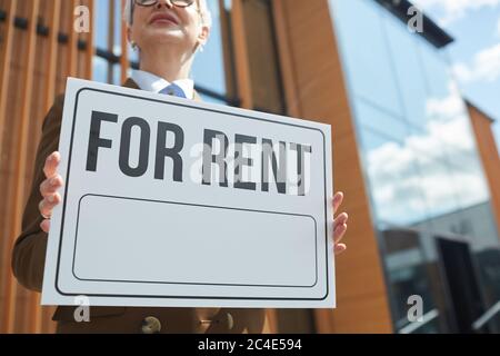 Close-up of mature businesswoman holding placard she working as a realtor and suggesting offices for rent Stock Photo