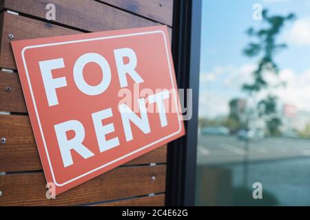 Close-up of placard For Rent hanging on the door of modern office building Stock Photo