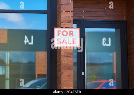 Image of modern office building with placard For Sale hanging on the brick wall Stock Photo