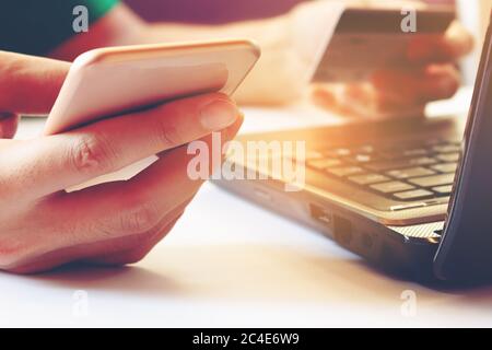 Young man using smartphone and holding credit card with laptop for searching data. Stock Photo