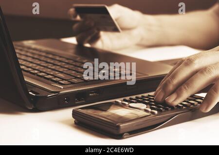 Young man calculating and holding credit card with laptop  about cost for shopping online. Stock Photo