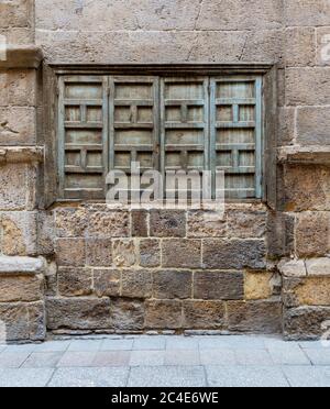 Exterior shot of weathered stone bricks wall and green grunge closed shuttered window on abandoned district Stock Photo
