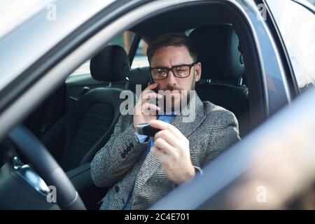 Mature businessman sitting in car salon and talking on mobile phone Stock Photo