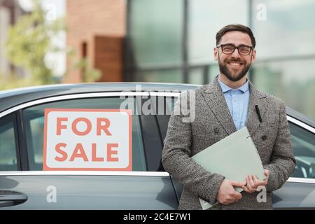 Portrait of mature bearded man holding documents and smiling at camera he buying the car Stock Photo