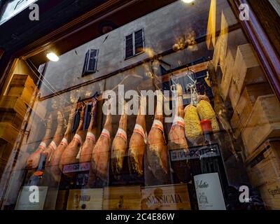 Cured hams hanging in a shop window display in Siena. Italy. Stock Photo