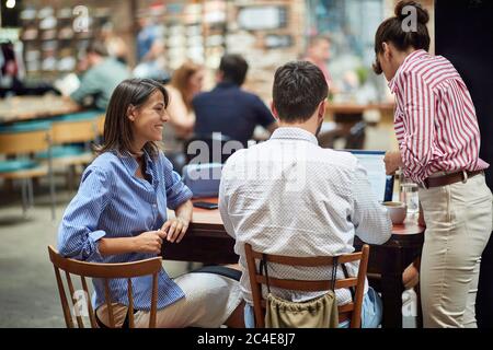 young caucasian freelancers having business meeting at public place, working in cafe. concept: modern technology gives you freedom to work from anywhe Stock Photo
