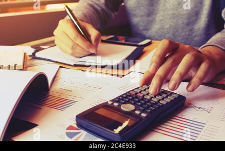 Young man using calculator and writing note and calculate finance at home. Stock Photo