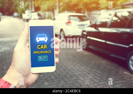 Insurance technology (Insurtech) concept and man hand holding smartphone for car insurance. Stock Photo