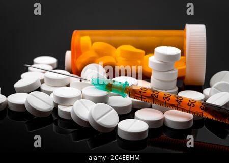 Opioid epidemic and drug abuse concept with a heroin syringe or other narcotic substances next to a bottle of prescription opioids. Oxycodone is the g Stock Photo