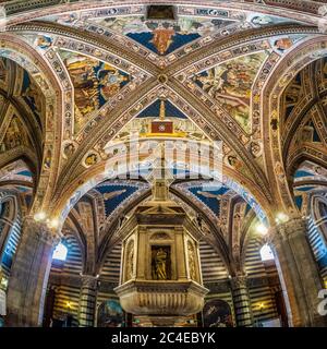 Baptistery ceiling frescoes and baptismal font. Siena Cathedral. Italy. Stock Photo