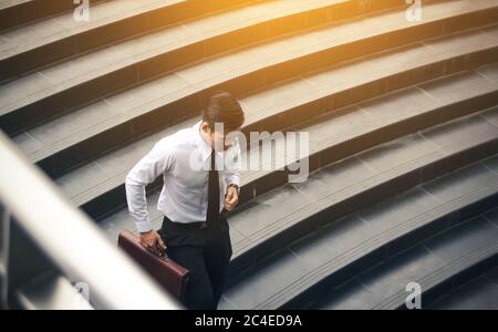 Young asian businessman holding briefcase and running to meeting at underground office building. Stock Photo