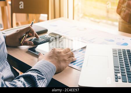 Asian businessman pressing button on calculator and calculate about analyze with looking data on tablet screen. Stock Photo