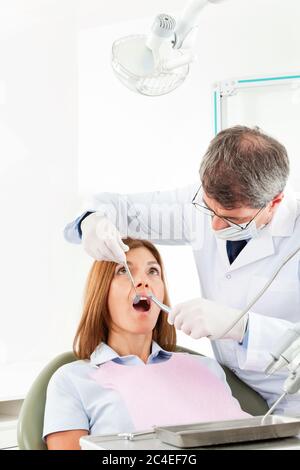 Dentist treats elderly woman in dental office Stock Photo