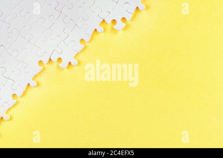 White jigsaw puzzle pieces on yellow. Abstract background with copy space Stock Photo