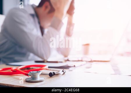 Emotion with young man doctor being exhausted and holding hands on head. Stock Photo