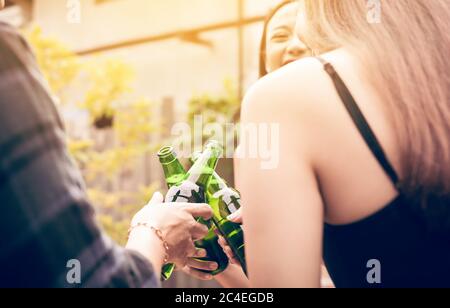 Asian group enjoying toasting drinks party with holding beer bottle clinking. Stock Photo