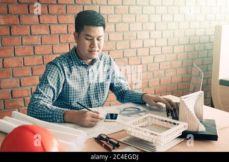 Architect asian man working in his office with sitting and typing on laptop. Stock Photo