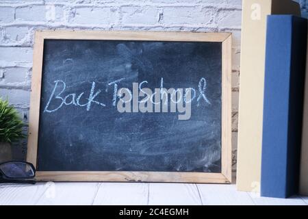 back to school concept with chalkboard and stack of book on table  Stock Photo