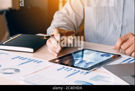 Businessman looking graph and summary report on digital tablet screen with analysis data result. Stock Photo