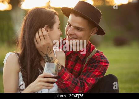 Tender moments. Caucasian young couple enjoying weekend together in the park on summer day. Look lovely, happy, cheerful. Concept of love, relationship, wellness, lifestyle. Sincere emotions. Stock Photo