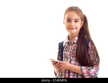Positive schoolgirl looking in camera while holding smartphone Stock Photo