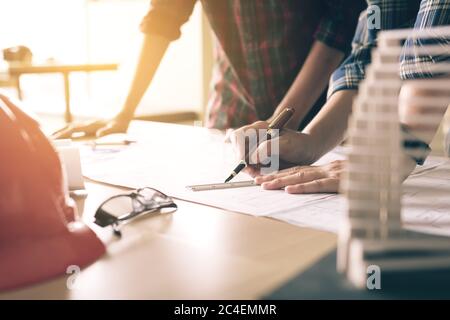 Two architects working with blueprints and discussing project at the meeting in the office. Stock Photo