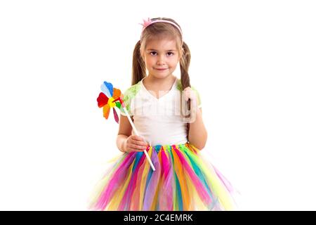 Little girl in colorful skirt and windmill toy looking in camera Stock Photo