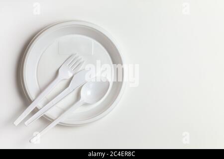 Plastic disposable white dishes, plate, spoon, knife, fork on white background. Flat lay, top view, copy space, horizontal. Ecology, zero waste, envir Stock Photo