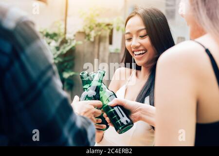 Asian group enjoying toasting drinks party with clinking beer bottle. Stock Photo