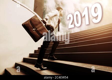 businessman holding briefcase and walking on staircase and looking to future 2019 newyear concept. Stock Photo