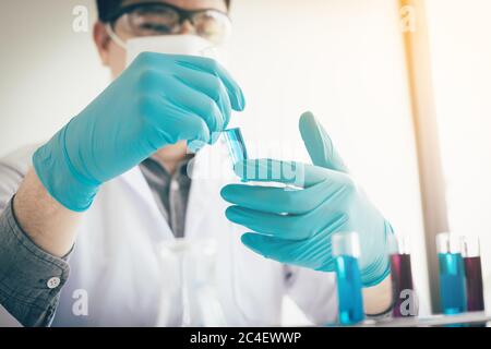 Asian scientist shaking and analyzing a liquid solution in lab. Stock Photo