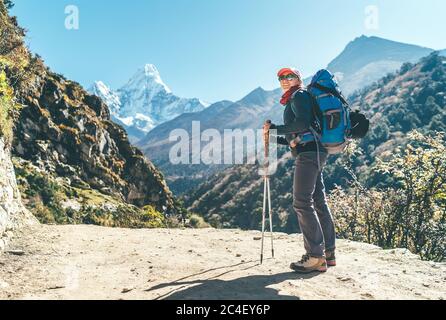 Young hiker backpacker female taking brake in hike walking enjoying valley during high altitude Everest Base Camp route near Dingboche, Nepal Stock Photo